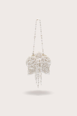 A white, pearl-beaded wristlet crafted to resemble a blooming flower. 