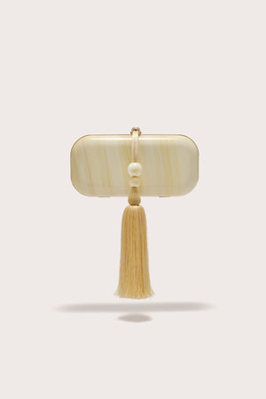 A soft, rectangular clutch crafter from marbled yellow acrylic, features a yellow beaded tassel adorning the hardware. 