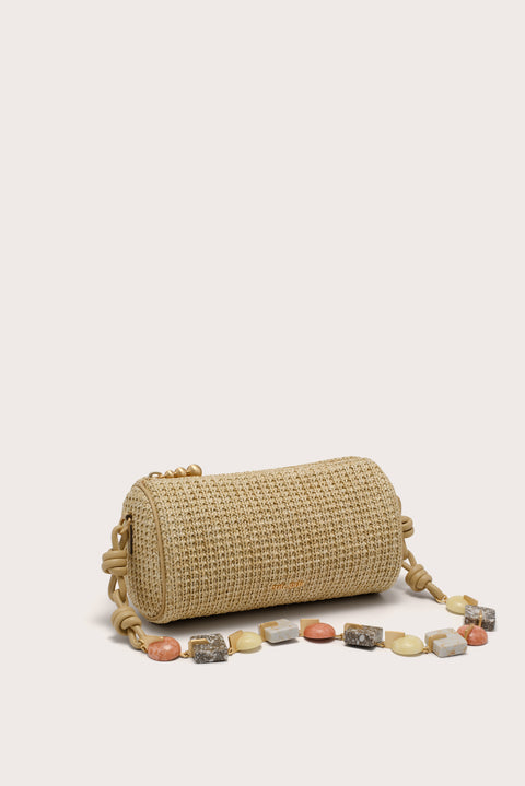 Woven handbag with a beaded strap on a beige background