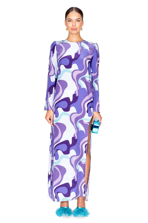 Model facing the camera in the wave side slit long dress in purple and blue print.