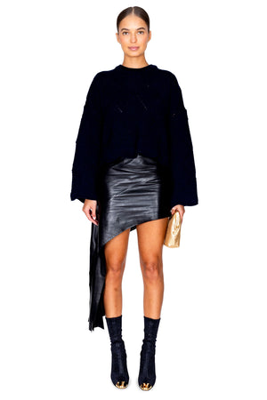 Model facing the camera in the dark navy sweater and a leather skirt