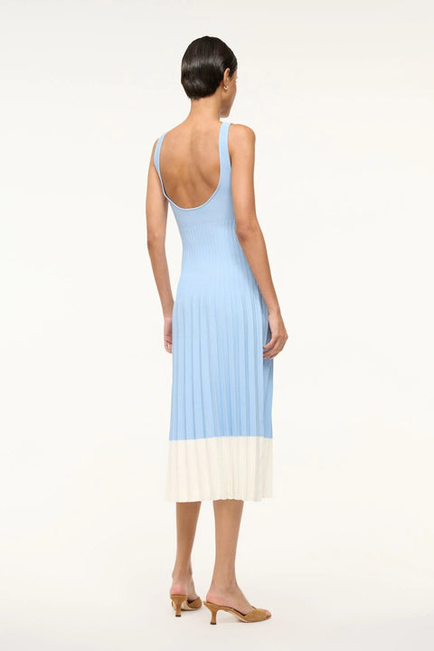 Back view of a woman wearing a light blue knit midi dress that features corset-style ribbing and white color blocking on the bottom