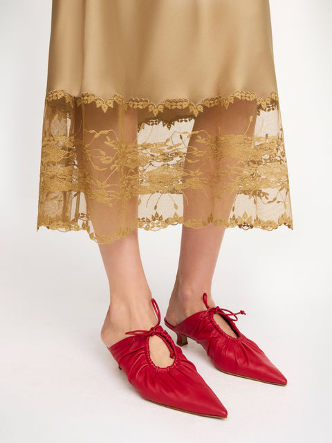 Close up of woman's feet in the red mules with pointy toe and cut out with drawstring. 