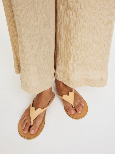 Light tan leather flip flops on feet.