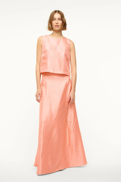 Woman wearing a pink silk tank top that features a crewneck and boxy fit, paired with a matching maxi skirt.