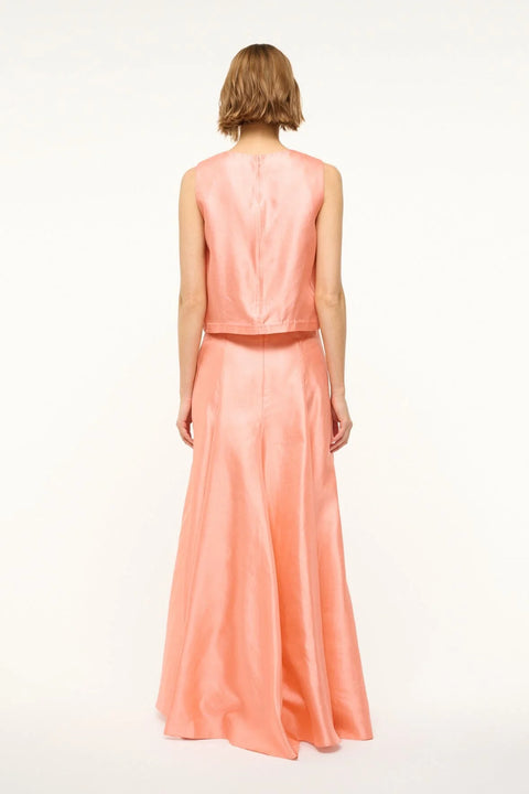 Back view of a woman wearing a pink silk, Aline, maxi skirt that features a back zipper and sits at the natural waist, paired with matching pink silk top. 