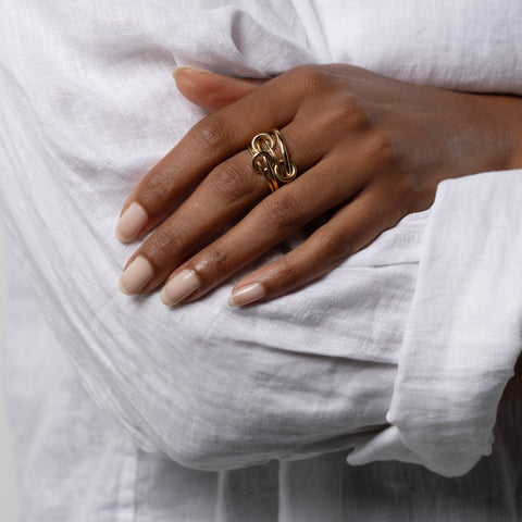 A woman wearing a Spinelli Kilcollin Pisces ring that features two 1.2mm yellow gold bands, a 1.7mm yellow gold band, and a 2.3mm yellow gold band, connected by three yellow gold connectors. 