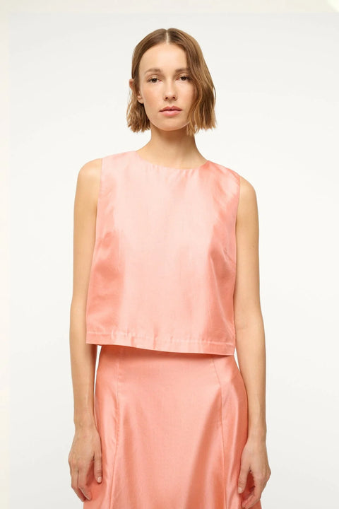 Close up of a woman wearing a pink silk tank top that features a crewneck and boxy fit, paired with a matching maxi skirt.