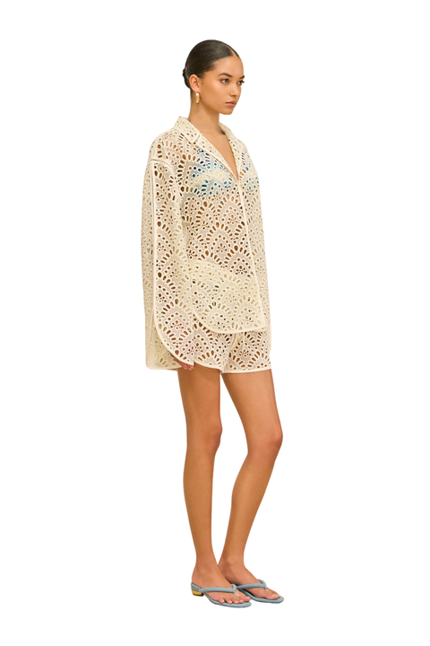 Woman wearing a beige crochet shorts cover-up under a swimsuit side angle