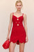 Close up of a woman wearing a red crochet mini dress that features a floral design and keyhole cutouts at the bust, paired with red accessories. 