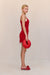 Side view of a woman wearing a red crochet mini dress that features a floral design and keyhole cutouts at the bust, paired with red accessories. 
