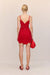 Back view of a woman wearing a red crochet mini dress that features a floral design and keyhole cutouts at the bust, paired with red accessories. 