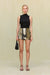Woman wearing a black sleeves top that features and asymmetrical high neck and ruched draping, paired with an embellished mini skirt and black accessories. 