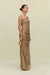 Side view of a woman wearing a gold metallic gown that features a hand rolled, one-shoulder neckline and intricate ruched draping throughout the body, paired with gold heels and accessories. 