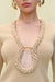 Detail shot of a woman wearing a cream knit, long sleeve mini dress that features a plunging wood-beaded detail and a keyhole cutout at the bust. 