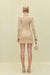 Back view of a woman wearing a cream knit, long sleeve mini dress that features a wood-beaded collar. 