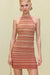 Close up of a woman wearing a knit halter neck mini dress that features an orange tonal stripe pattern.