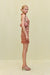Side view of a woman wearing an orange striped knit mini dress that features a halter neck and low back. 