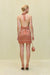 Back view of a woman wearing an orange stripe knit midi dress that features a tie up halter neck and a low back with an adjustable tie bow detail on the mid back. 