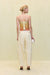 back view of a woman wearing a yellow-orange strapless top that features draped beaded fringe across the torso and a back zipper, paired with yellow pants. 