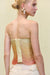 Close up back view of a woman wearing a yellow-orange strapless top that features draped beaded fringe across the torso and a back zipper, paired with yellow pants. 