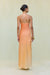 Back view of a woman wearing a one shoulder orange ombre gown that features a knot at the hip and ruched draping throughout. 