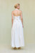 Back view of a woman wearing a cropped white halter top that features a low back, paired with a white maxi skirt. 
