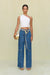 Woman wearing a white one-shoulder knit crop top, paired with jeans. 