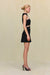 Side view of a woman wearing a black mini dress that features a high neck with cutouts in the midriff. 