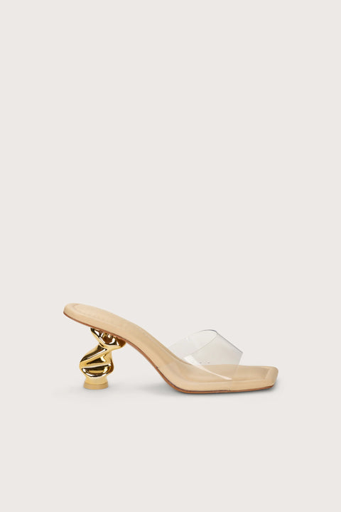 Side profile of a square-to sandal with a clear vinyl strap and a sculptural gold heel. 