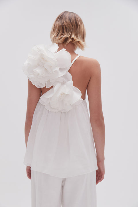 Model facing away showing the back of the quintessa flower top in white with spaghetti straps.