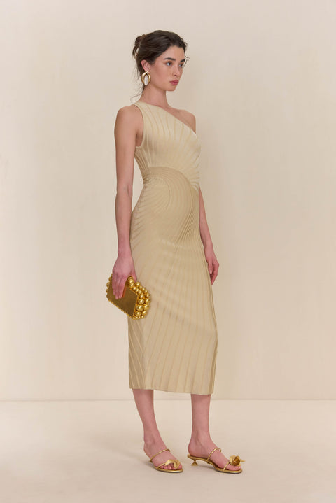 Side view of a woman wearing a cream knit midi dress that features a one-shoulder neckline and patterned ribbing. 