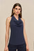 Close up of a side-facing woman wearing a navy blue sleeveless top that features a cowl halter neck, paired with blue pants, natural sandals, and a woven handbag. 