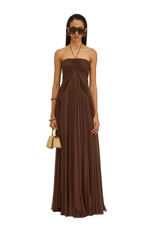 Woman wearing a brown strapless dress against a beige background