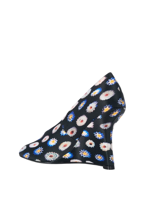 A single wedge heel shoe with a black base covered in a colorful daisy-like floral pattern, shown against a plain white background.