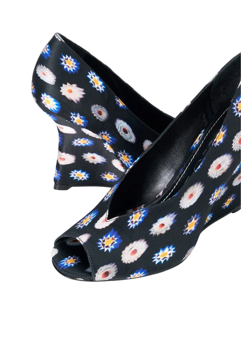 A pair of women's open-toe wedge pumps featuring a black base covered in a colorful daisy pattern with blue, white, and yellow details, set against a plain white background.