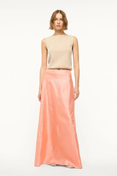 Woman wearing a pink silk, Aline, maxi skirt that features a back zipper and sits at the natural waist, paired with a tan sweater vest. 