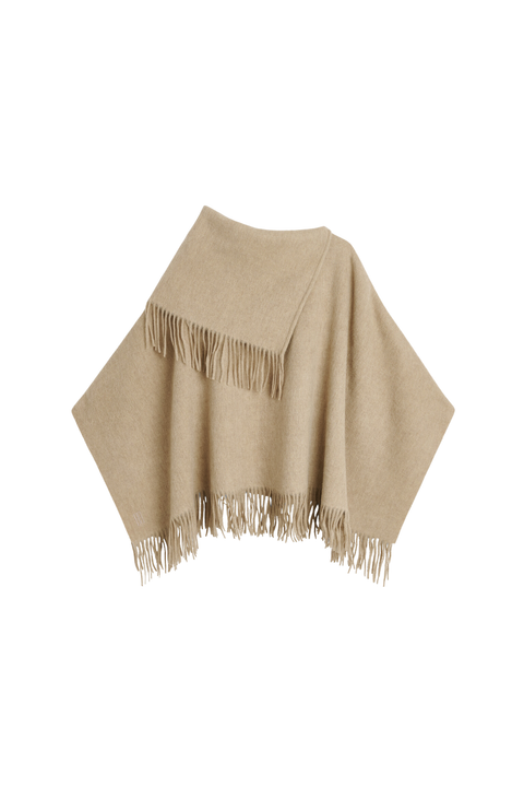 A light beige knit poncho with fringed edges, displayed against a solid white background.