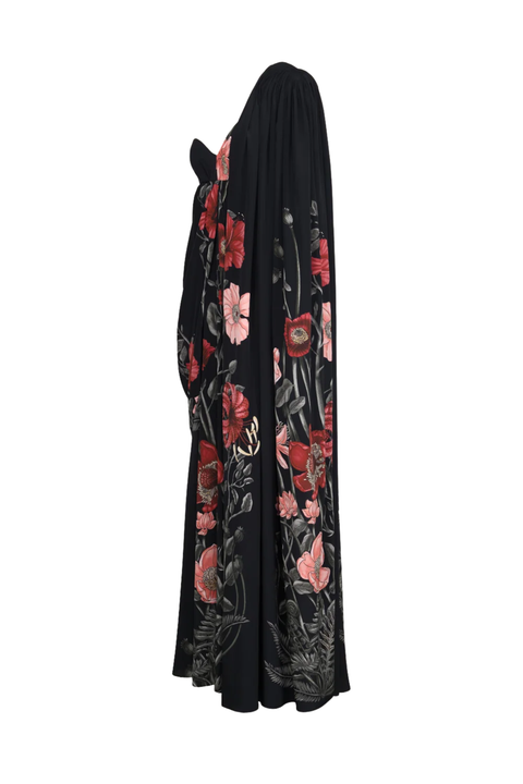 A long black abaya dress featuring a vibrant red and pink floral print with green leaves, shown from a back profile view against a plain white background.