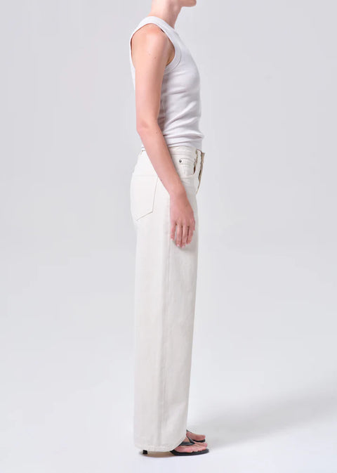 Person wearing white wide-leg, mid-rise jeans and a white top on a white background from the side