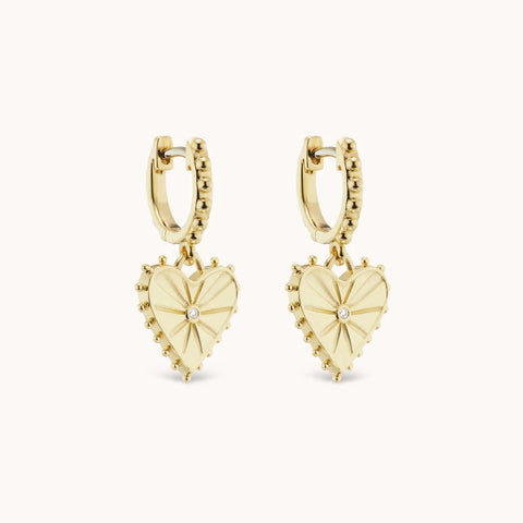 Side view of the gold hoop earrings with small spiked heart dangles.