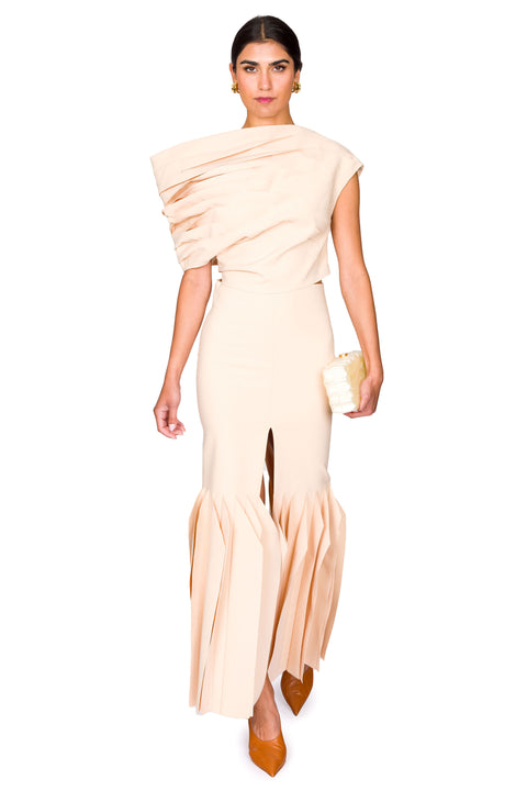 Woman walking in matching nude set with white clutch.