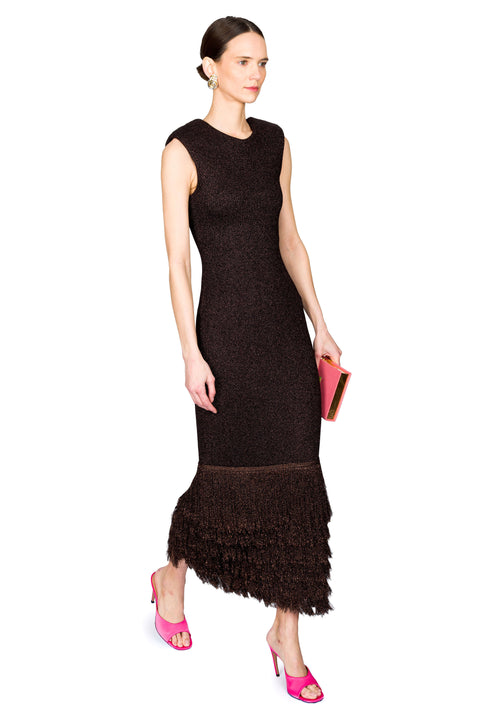 Woman walking to the right wearing a brown dress with a textured fringe hem on a white background