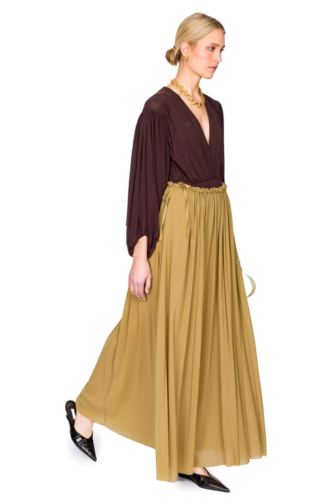 Woman walking in maxi tulle skirt and long sleeve v-neck top and brown shoes.