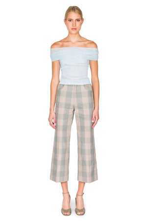 Woman wears blue tulle top with blue and grey checkered pants.