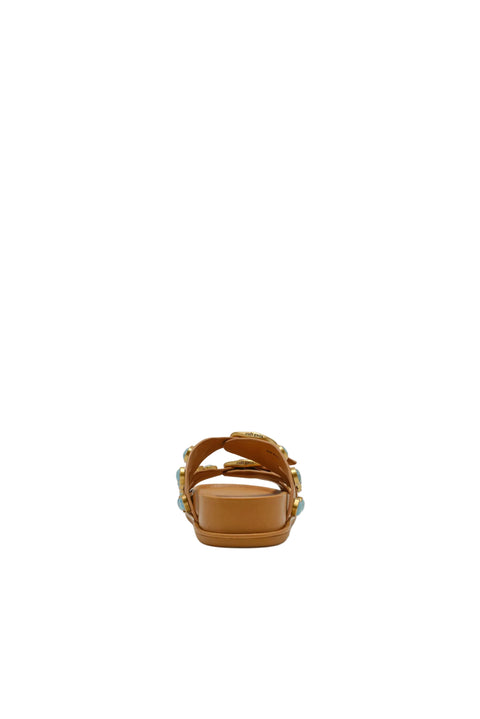 Tan sandal with decorative straps on a light beige background