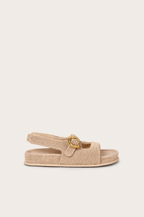 Side view of a raffia sandal that features two top straps and a heel strap with a gold abstract buckle. 
