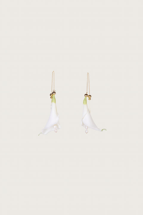 Ghost image of two white calla lily inspired earrings on a gold threader chain.