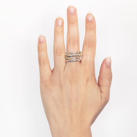 A woman's hand wearing a Spinelli Kilcollin Cici Petite ring that features a 1.7mm sterling silver band, a 2.8mm sterling silver textured band, a 1.7mm sterling silver band, and a 2.8mm sterling silver band, connected by three yellow gold connectors. 