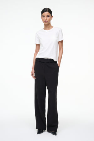 Person wearing a white t-shirt and black pants on a white background